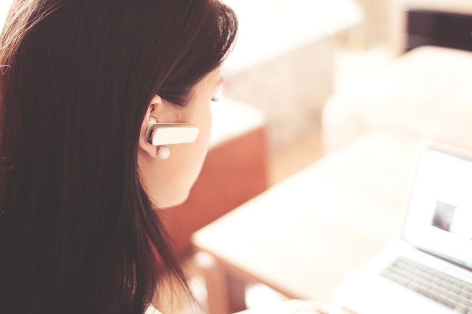 A woman at a computer with a earpiece on